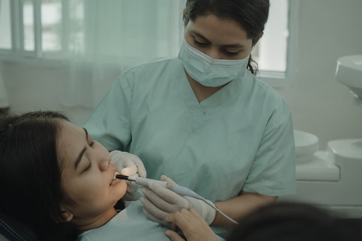 A dental nurse positioning an x-ray sensor while a patient sits in the chair